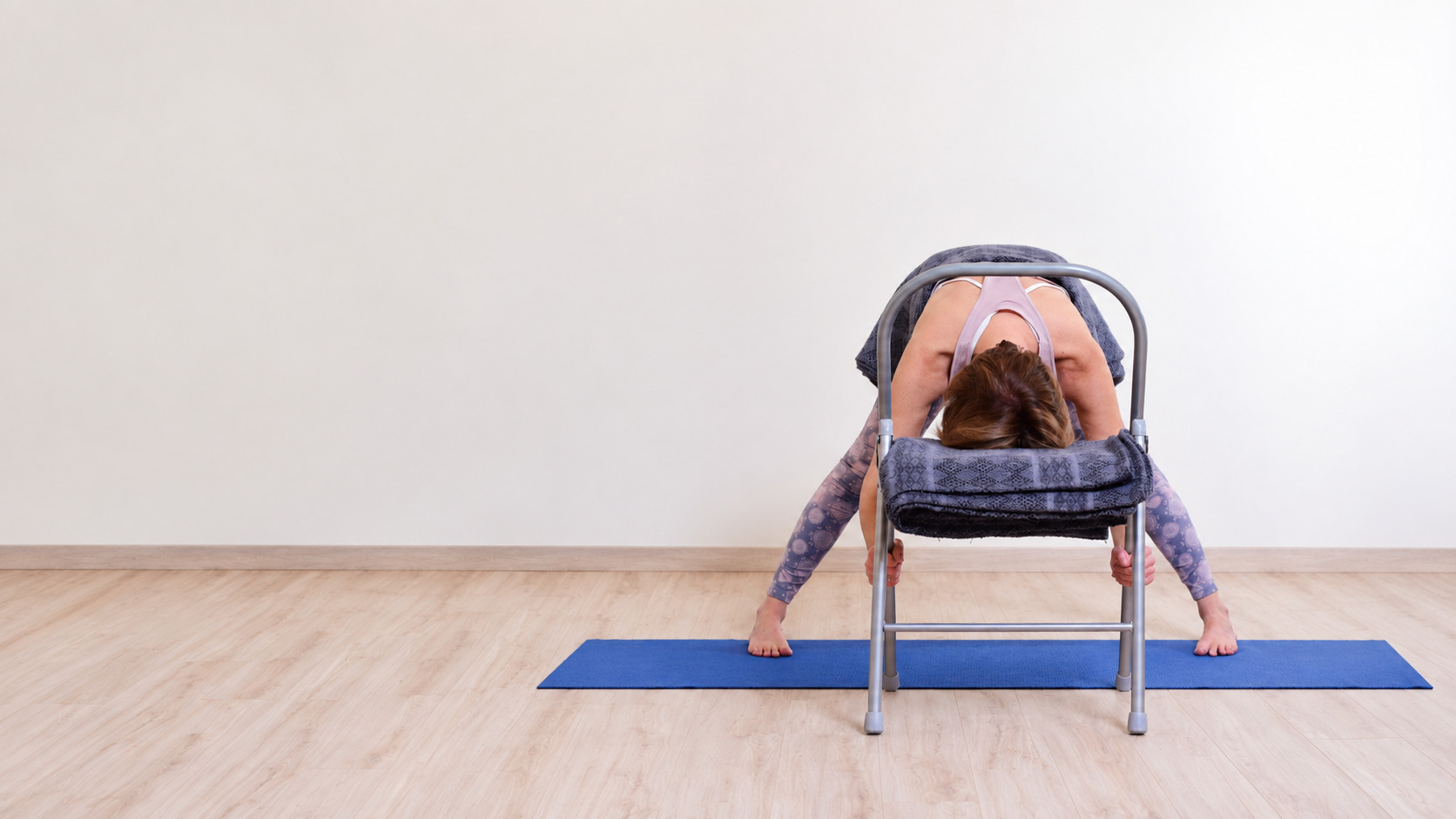 Audrey Favreau in una flessione in avanti sostenuta con una sedia durante una pratica di Restorative Yoga